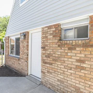 Square frame Side exterior of a small guest house with wall lamp, bricks and Stock Photos