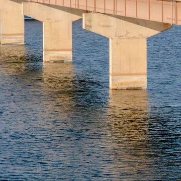Square frame Stringer bridge spanning over calm lake with view of snowy land and Stock Photos