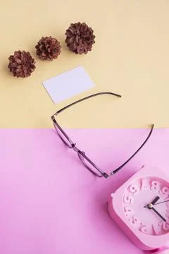 Square glasses, alarm clock, pine tree flowers on a pastel pink and pastel ye Stock Photos