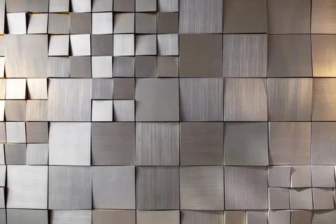 Square gold tiles of different sizes on the wall. rough surface texture Stock Photos