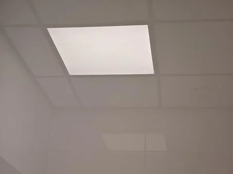 Square LED ceiling panel glowing in a white suspended ceiling Stock Photos