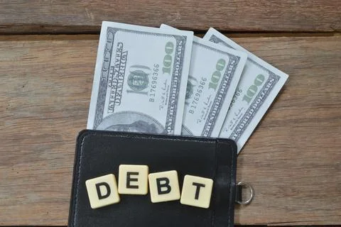 Square letters with text DEBT over wooden background. Stock Photos