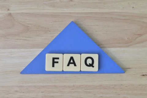 Square letters with text FAQ over wooden background. Stock Photos