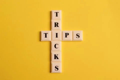 Square letters with text TIPS and TRICKS isolated on yellow background Stock Photos
