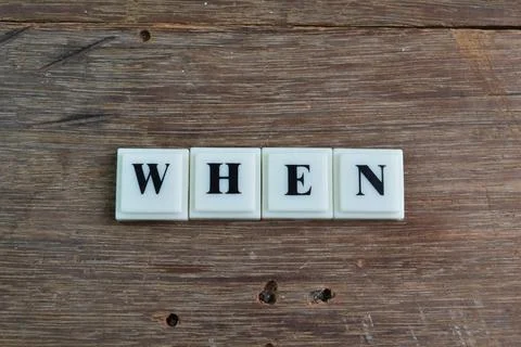 Square letters with text WHEN isolated on a wooden background Stock Photos