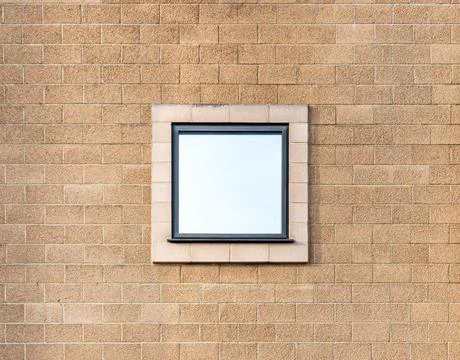 Square mirror reflective window centred on an orange brick wall Stock Photos
