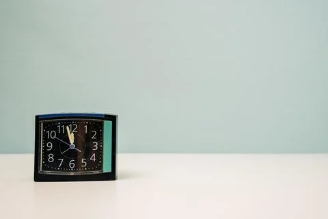Square modern alarm clock on the table on a turquoise background, time 23:55, Foto stock