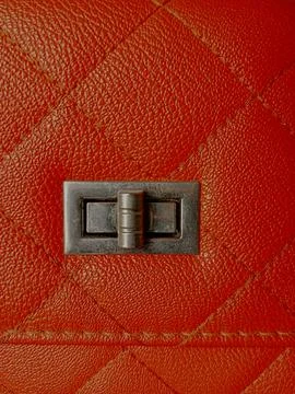 Square or box pattern on orange bag with flap showing lock button. Stock Photos