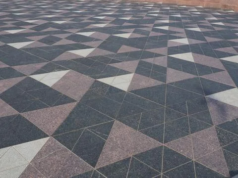 The square is paved with triangular tiles. Grey, white, black tiles on the st 스톡 사진