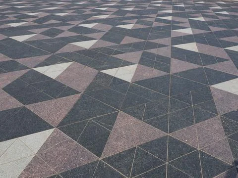 The square is paved with triangular tiles. Grey, white, black tiles on the st 스톡 사진