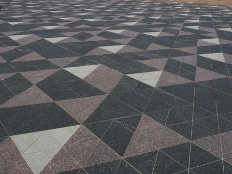 The square is paved with triangular tiles. Grey, white, black tiles on the st 스톡 사진