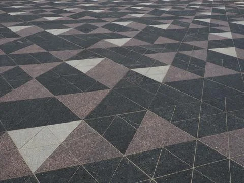 The square is paved with triangular tiles. Grey, white, black tiles on the st 스톡 사진