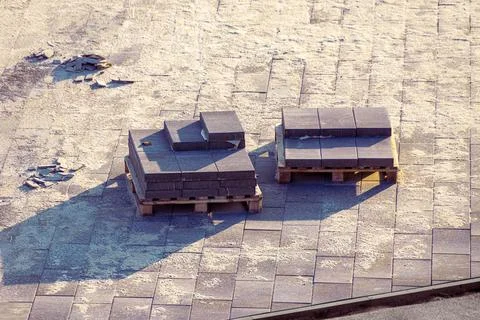 Square paving slabs from a cement mixture lie on pallets, among the square Stock Photos