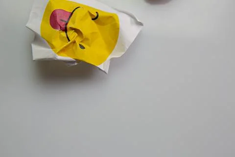 Square piece of paper with the face of a mocking emoji with tongue out. Stock Photos