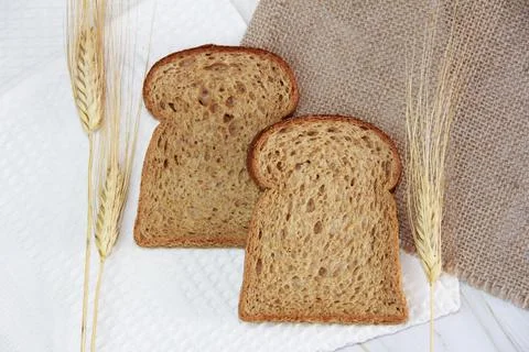 Square pieces of rye toast bread and dry ears of wheat Stock Photos
