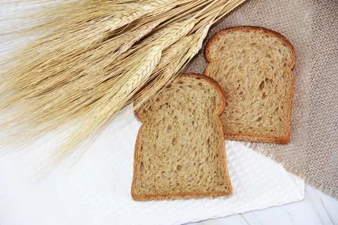 Square pieces of toast rye bread and ears of dry wheat Stock Photos