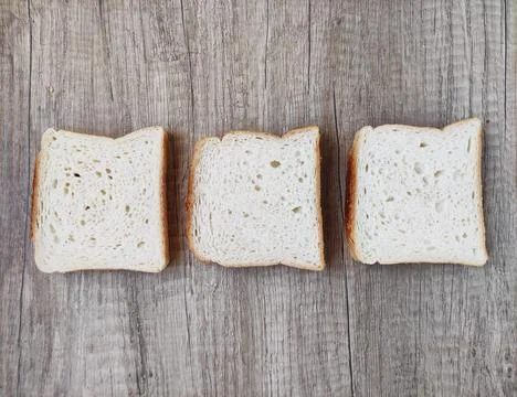 Square pieces of white toast bread on  wooden background Foto stock