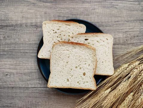 Square pieces of white toast bread and ears of dry wheat Foto stock