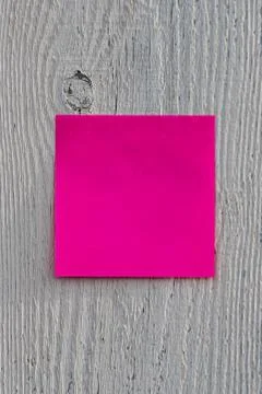 Square pink or red note paper with copy space is hanging on a gray wooden fen Stock Photos