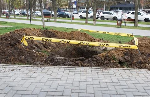 A square pit dug into the soil, next to the public sidewalk and fenced with.. Stock Photos