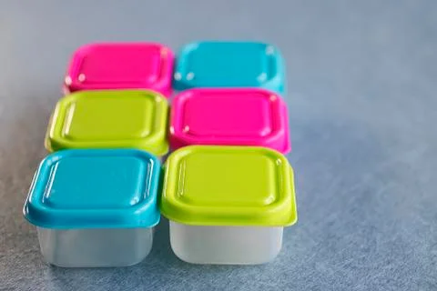 Square plastic containers with bright multi-colored lids. Stock Photos