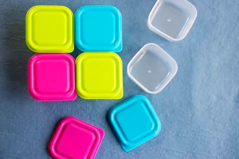 Square plastic containers with bright multi-colored lids. Stock Photos