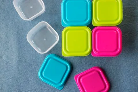Square plastic containers with bright multi-colored lids. Stock Photos