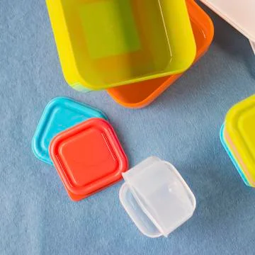 Square plastic containers with bright multi-colored lids. Stock Photos