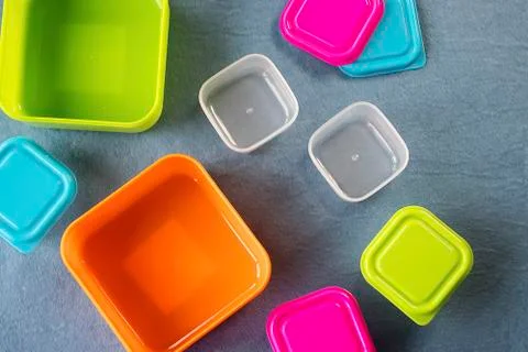Square plastic containers with bright multi-colored lids. Stock Photos