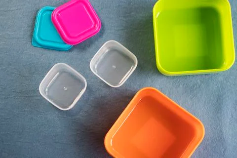 Square plastic containers with bright multi-colored lids. Stock Photos