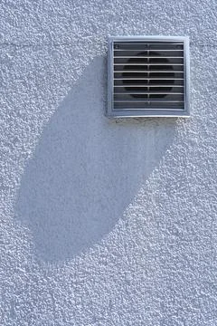 Square plastic ventilation grille on a white facade Stock Photos