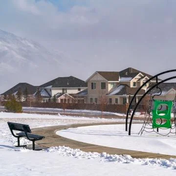 Square Playground with climbing frames against homes and snowy mountain in Stock Photos