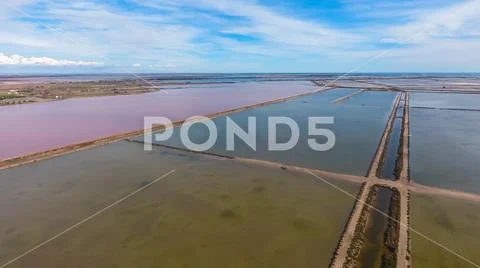 Square pool for evaporation of salt and a pond with pink water. Stock Photos