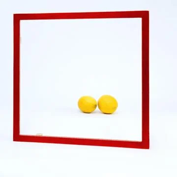 Square red frame set against a white background Two lemons lie in the frame Stock-Fotos