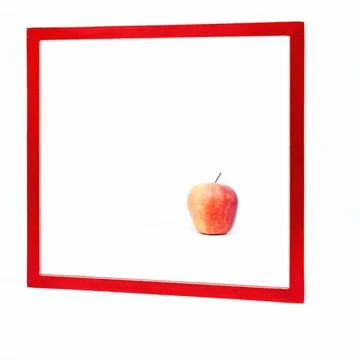 Square red frame set against a white background An apple stands in the frame 스톡 사진