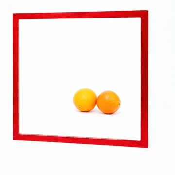 Square red frame set against a white background Two oranges lie in the frame 스톡 사진