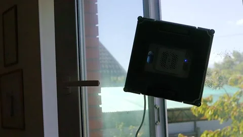 Square robot for washing windows works on an open window in the house, savin Stock Footage 313458077