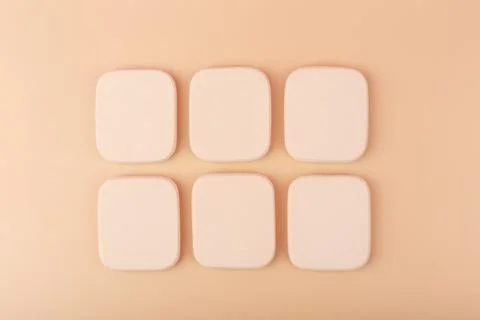 Square shaped beige make up sponges in a row on light beige background Stock Photos