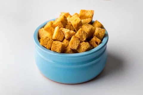 Square-shaped bread crumbs in a blue pot on a white background. Oven-fried Stock Photos