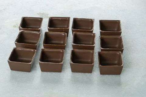 Square-shaped milk chocolate shells ready to be filled. Stock Photos