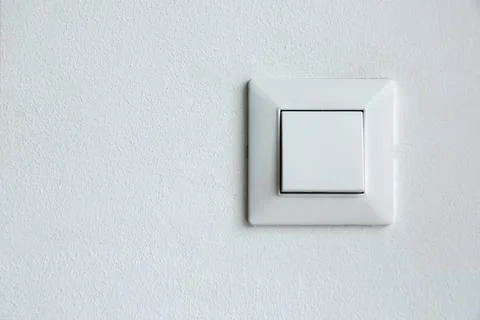 A square shaped white plastic light switch mounted on a white textured wall. Stock Photos