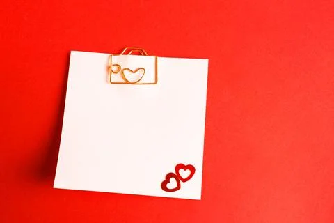 Square sheet for notes with a paper clip in shape of a letter and a heart. .. Stock Photos