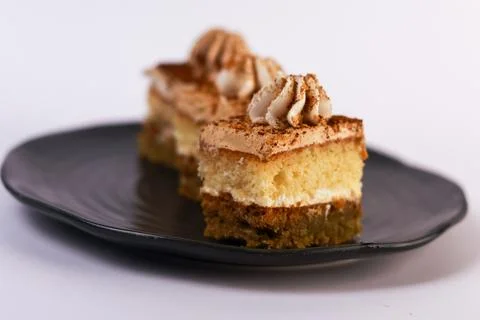 Square slices of layered sponge cake with whipped cream filling, artfully arrang Stock Photos