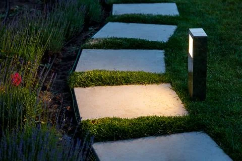 Square tile marble path illuminated by a lantern in the backyard. Stock Photos