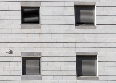 Square windows with roller shutters on tiled facade Stock Photos