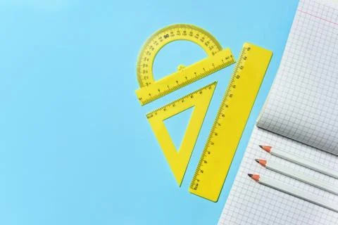 Squared school notebook, pencils and set of rulers on a blue background with Stock Photos