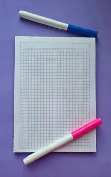 Squared school notebook with pink and blue felt-tip pens on purple background Stock Photos
