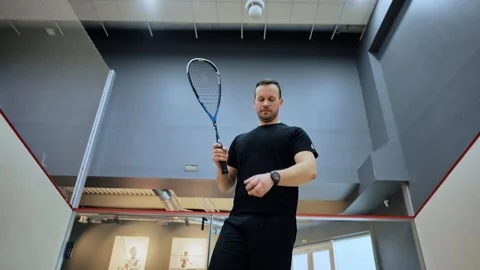 Squash player checks watch before game - indoor court readiness moment Latvia Stock Footage 308451463