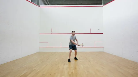 Squash player practices hitting ball with racket in court Stock Footage 220967929