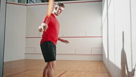 Squash player strikes ball with racket in four-walled court Stock Footage 220960693